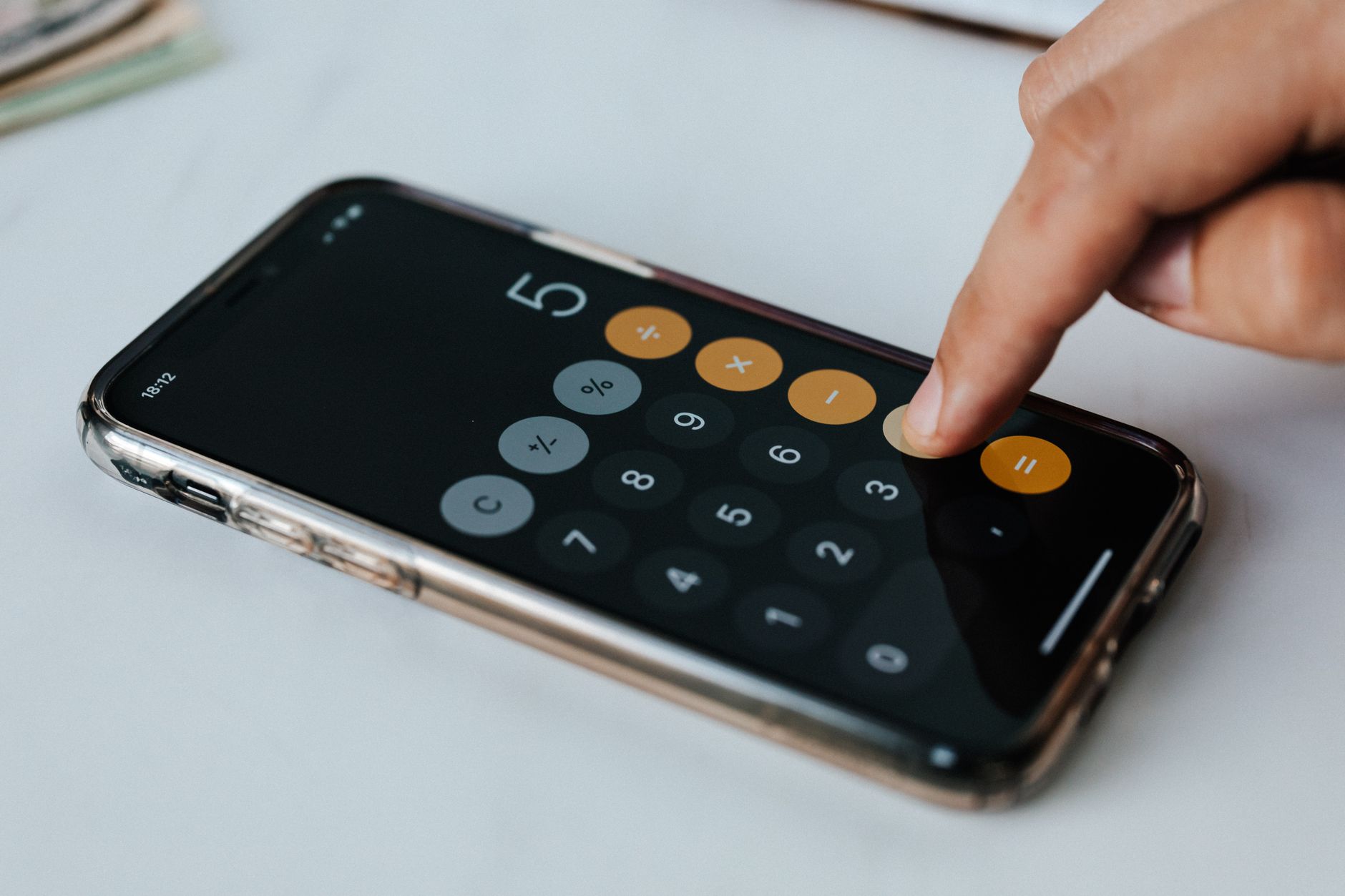 Financier sans visage touchant l'écran d'un téléphone portable pendant le travail tout en calculant sur une application de calculatrice représentant des chiffres et des symboles financiers